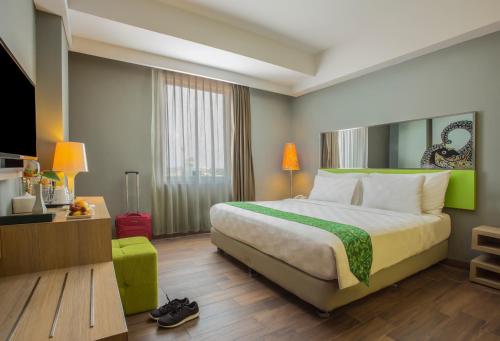 a hotel room with a large bed and a tv at KHAS Tegal Hotel in Tegal