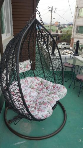 a swing chair with a cushion on a porch at Joa Guesthouse in Gwangju