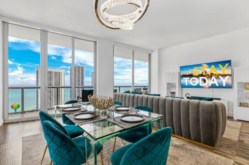 a dining room with a glass table and blue chairs at Beachwalk Resort - PENTHOUSE IN THE SKY 3BDR and 3BA LUXURY CONDO DIRECT OCEAN VIEW in Hallandale Beach
