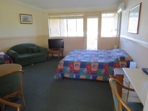 a bedroom with a bed and a chair and a tv at Golfview Lodge in Bowral