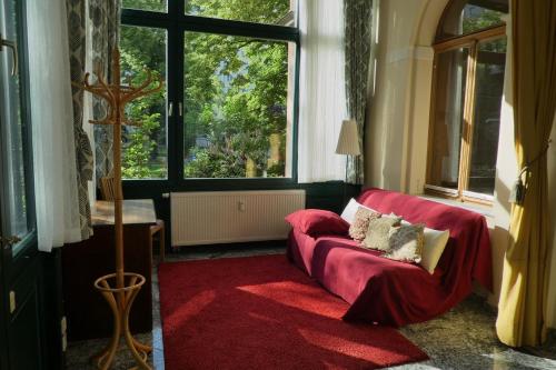 a living room with a red couch and a large window at Ferienwohnung Villa Haniel Edmund in Dresden