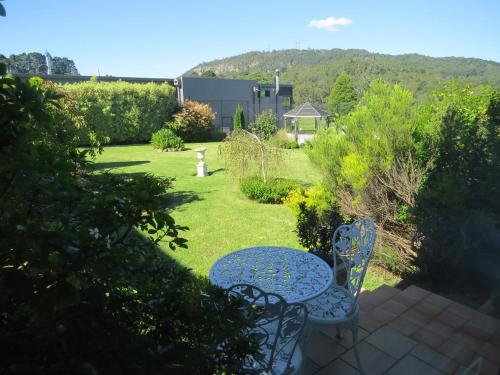 a patio with a table and chairs in a garden at Golfview Lodge in Bowral