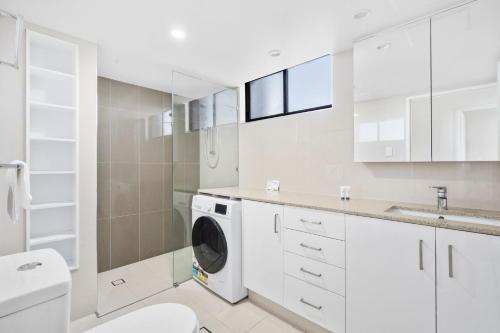 a white bathroom with a washing machine in it at Royal Palms 24 F in Gold Coast