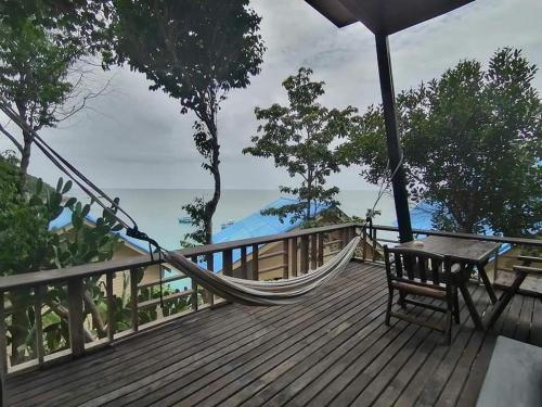 a hammock on a deck with a view of the ocean at Chabalay Resort in Koh Tao