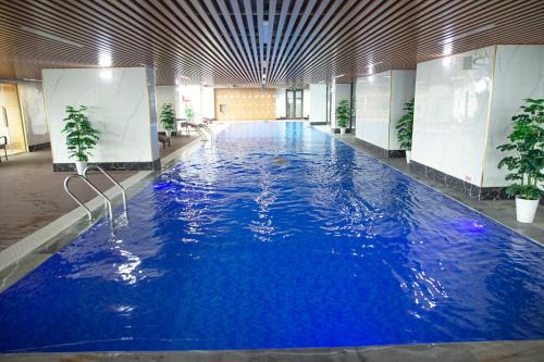 a large swimming pool with blue water in a building at TSQ STAY Hotel Apartment in Hanoi