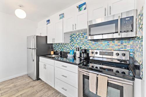 a kitchen with white cabinets and a stainless steel appliances at 1BR with Great Ocean Views, 1 Block to Waikiki Beach in Honolulu