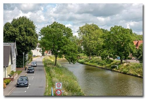 a river with cars parked on the side of a road at Bi uns im Norden in Brunsbüttel