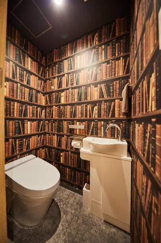 a bathroom with a toilet and a wall of books at Hotel TORACO konohana in Osaka