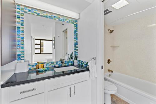 a bathroom with a sink and a tub and a mirror at 1BR with Great Ocean Views, 1 Block to Waikiki Beach in Honolulu