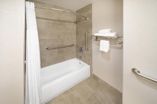 a bathroom with a white tub and a shower at Days Inn & Suites by Wyndham San Antonio near Frost Bank Center in San Antonio