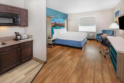 a hotel room with a bed and a kitchen at Days Inn & Suites by Wyndham San Antonio near Frost Bank Center in San Antonio