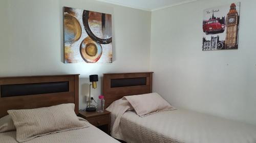 a bedroom with two beds and a picture on the wall at Hostal Costa Brava in Iquique
