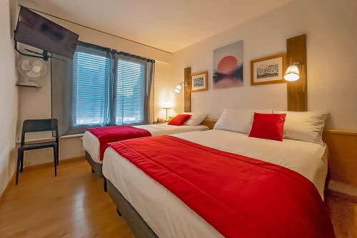 a hotel room with two beds with red sheets at Hotel des Alpes Bulle center in Bulle