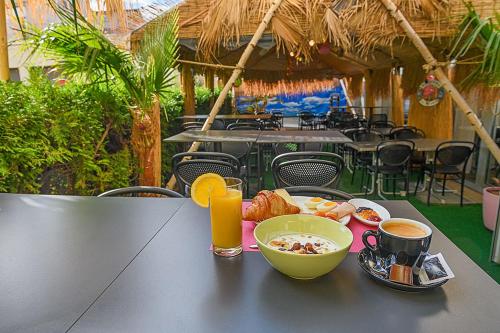 a table with a bowl of food and a cup of orange juice at Hotel des Alpes Bulle center in Bulle