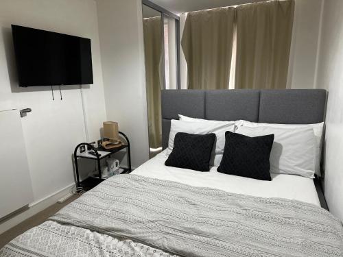a bedroom with a bed with two pillows and a flat screen tv at YES Apartments in Crayford
