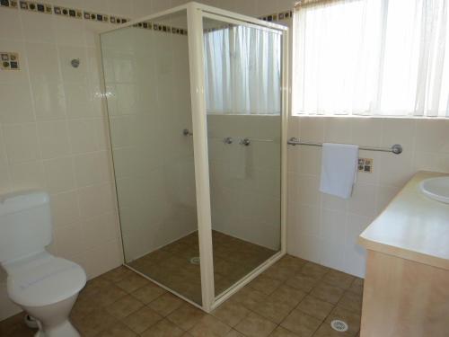 a bathroom with a shower with a toilet and a sink at George Bass Motor Inn in Nowra