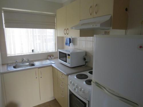 a kitchen with a white refrigerator and a microwave at George Bass Motor Inn in Nowra