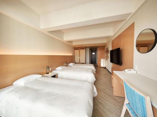 fila de camas en una habitación con espejo en パレスインムーンビーチ, en Onna