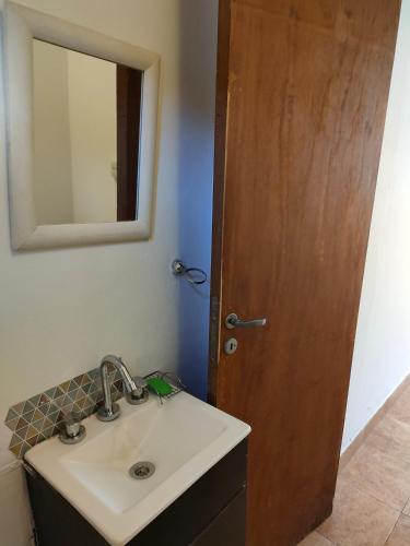 baño con lavabo, espejo y puerta de madera en Virgen Cerro en Salta