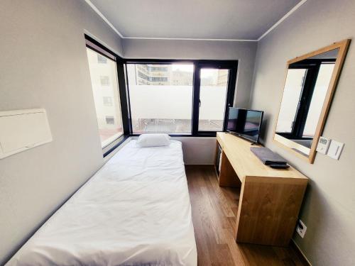 a small room with a bed and a desk and window at J.Hill House in Seoul