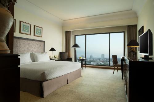スラバヤにあるブミ スラバヤ シティ リゾートのベッドと大きな窓が備わるホテルルームです。