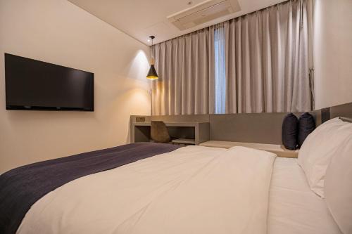 a hotel room with a bed and a flat screen tv at Gloucester Hotel Cheongju in Cheongju