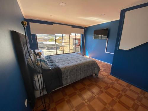 a bedroom with blue walls and a bed with a window at Departamento en Tomé centro in Tomé