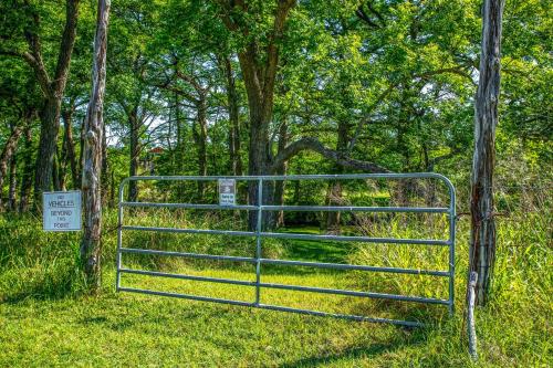 a gate in the grass with a sign on it at Clear River Cabin on Medina in Bandera