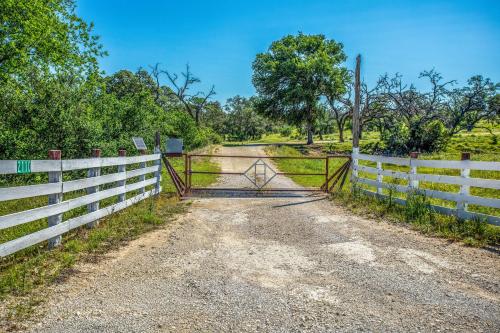 a gate on a dirt road next to a fence at Clear River Cabin on Medina in Bandera