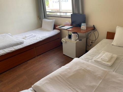 北中城村にあるホテルサザンヴィレッジ沖縄のベッド2台、デスク、コンピュータが備わる客室です。