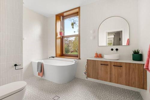 La salle de bains est pourvue d'une baignoire, d'un lavabo et d'un miroir. dans l'établissement Piambong House, à Clare