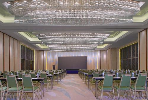 una sala de conferencias con mesas, sillas y una pantalla en The Westin Qingdao - Instagrammable, en Qingdao