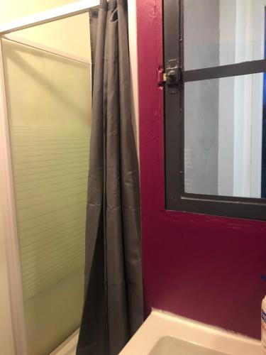 a bathroom with a red door and a mirror at Petit appartement centre ville Granville in Granville