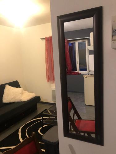 un miroir reflétant un salon avec un canapé dans l'établissement Petit appartement centre ville Granville, à Granville