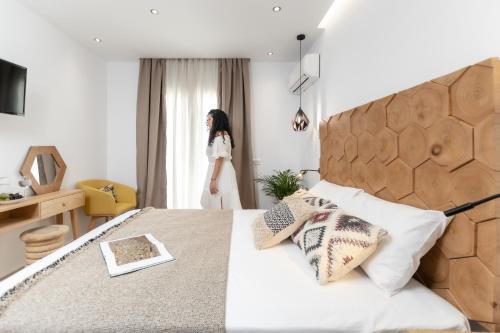 a woman standing in a bedroom looking out the window at Galazia Boutique Apartments in Naxos Chora