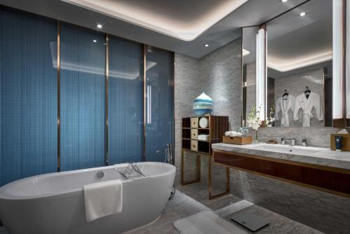 a bathroom with a tub and a large mirror at Primus Hotel Shanghai Hongqiao in Shanghai