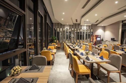 a restaurant with long tables and yellow chairs at Grand Ocean Luxury Boutique - Infinity Rooftop Pool in Da Nang