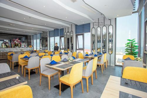 a restaurant with yellow chairs and tables and a bar at Grand Ocean Luxury Boutique - Infinity Rooftop Pool in Da Nang