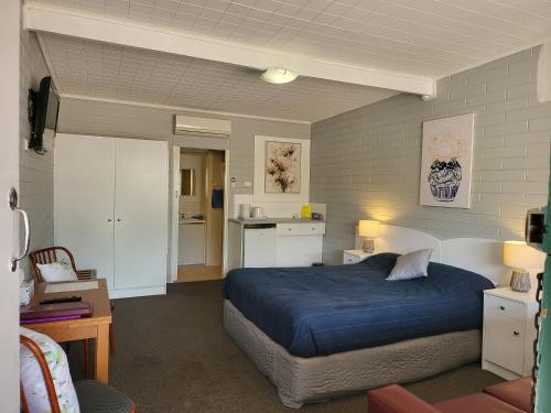 a bedroom with a blue bed and a kitchen at Peterborough Motel in Peterborough