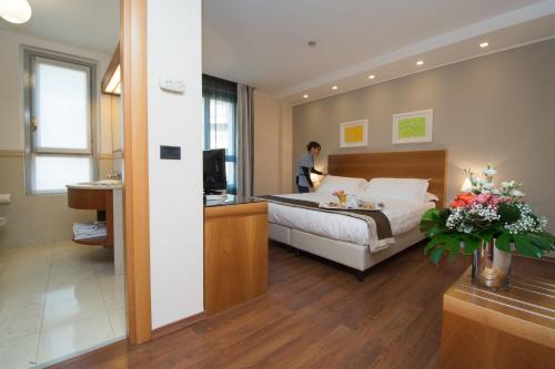 Ein Mann steht in einem Hotelzimmer mit einem Bett in der Unterkunft Hotel Royal Falcone in Monza