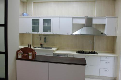 a kitchen with white cabinets and a sink and a stove at Sunny Breeze Garden Homestay in Jiali