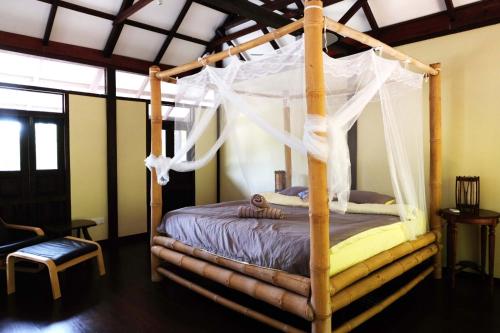 a bedroom with a canopy bed with a net at Bamboo Cottage Langkawi in Pantai Cenang
