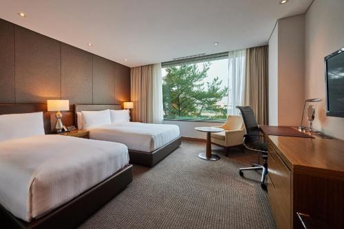 una camera d'albergo con due letti e una scrivania di LOTTE City Hotel Gimpo Airport a Seul