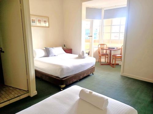 um quarto de hotel com duas camas e uma mesa e cadeiras em Knickerbocker Hotel em Bathurst