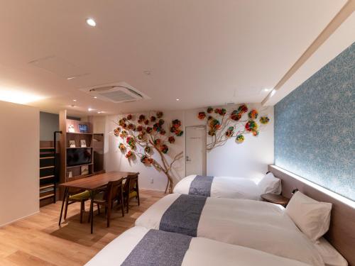 two beds in a room with a table and a dining room at COCOSHUKU Asakusa Kuramae in Tokyo