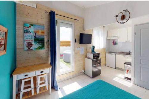 a room with a kitchen with a table and a window at Studio terrasse 27m2 RESERVATION SUR RBNB in Perpignan