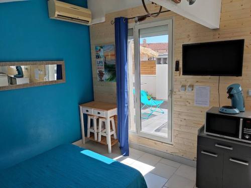 a bedroom with a bed and a tv and a balcony at Studio terrasse 27m2 RESERVATION SUR RBNB in Perpignan