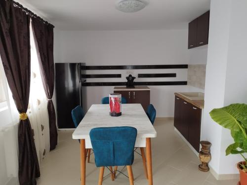 a kitchen with a white table and blue chairs at Casa Atelier Transfăgărășan in Corbeni