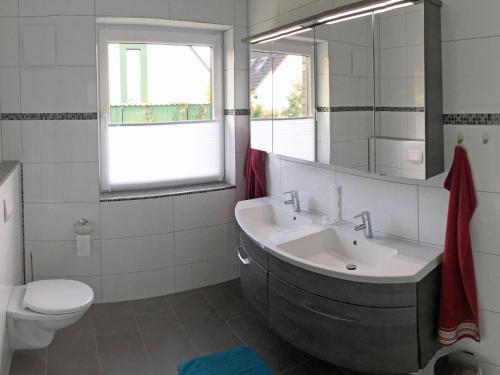 ein Badezimmer mit einem Waschbecken, einem WC und einem Spiegel in der Unterkunft Haus am Meer Ferienwohnung Deluxe in Dangast