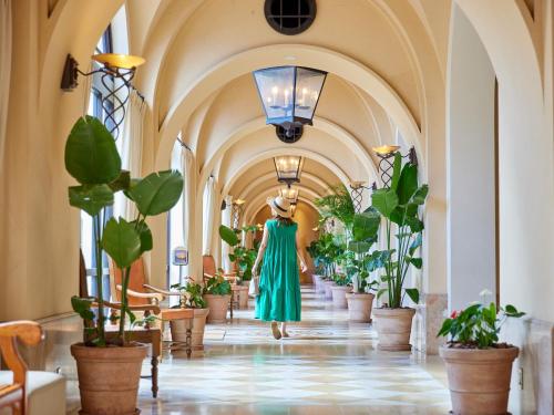 讀谷的住宿－阿利維亞日光酒店，走下走廊的女人,种着盆栽植物